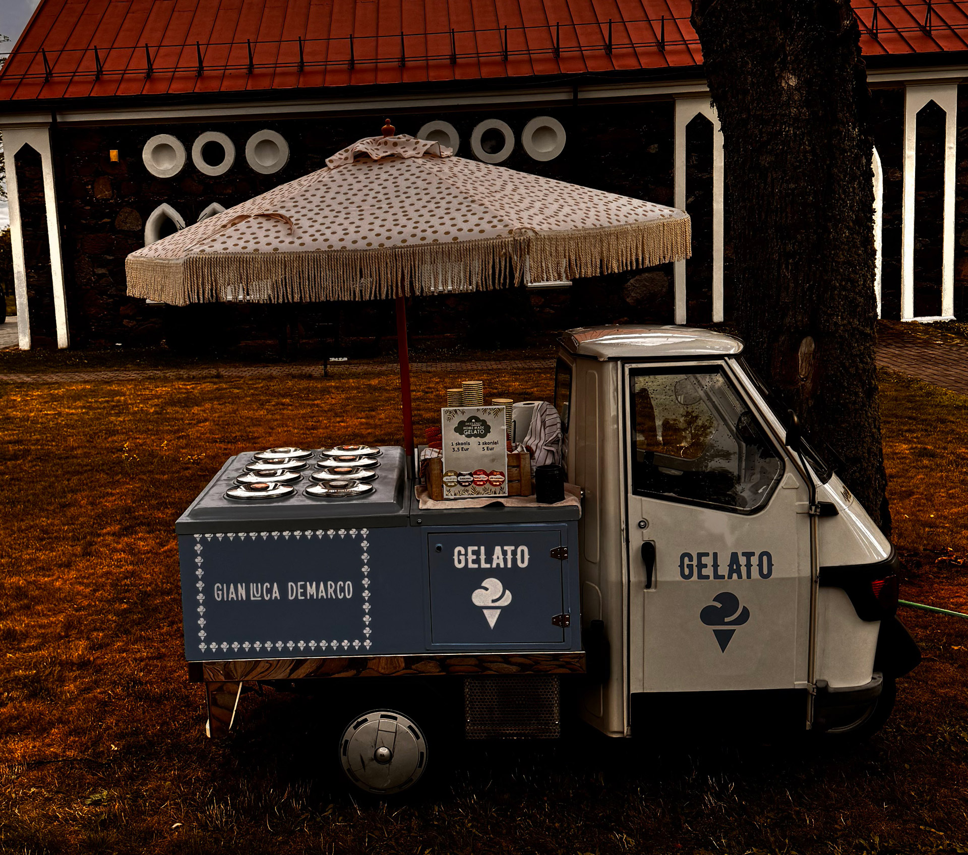 Piaggio Ape 50 gelato truck at outdoor event with Italian ice cream banner